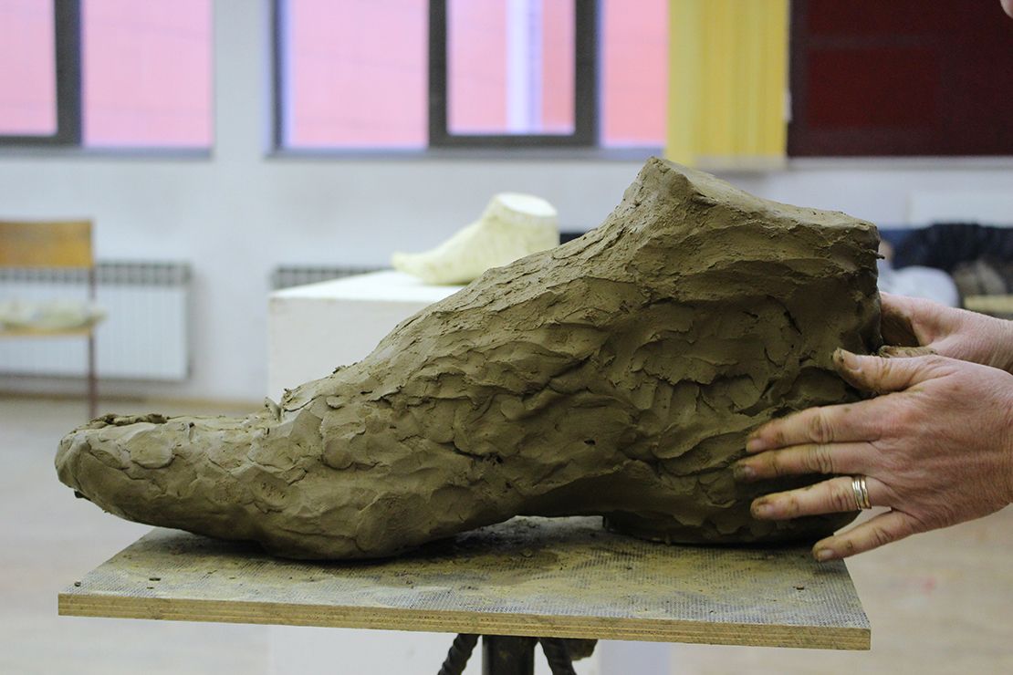 Modeling a foot in clay.