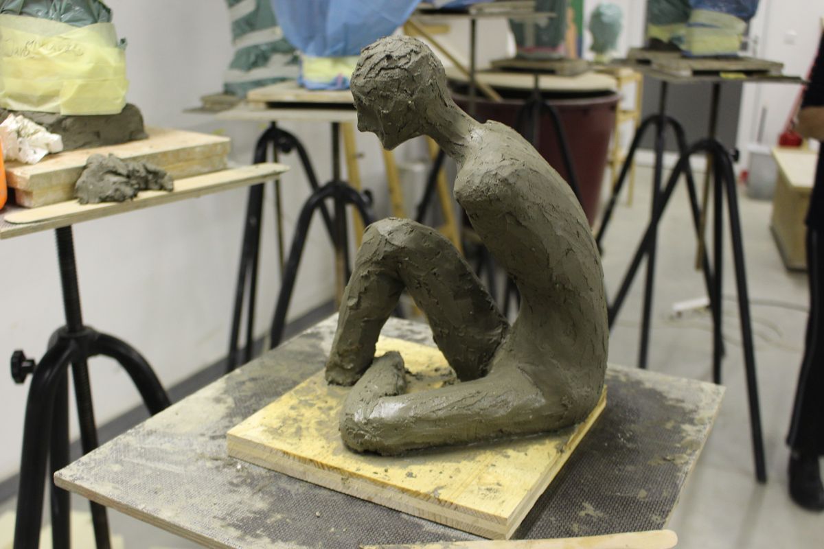 Modeling a small-size seated figure in clay.