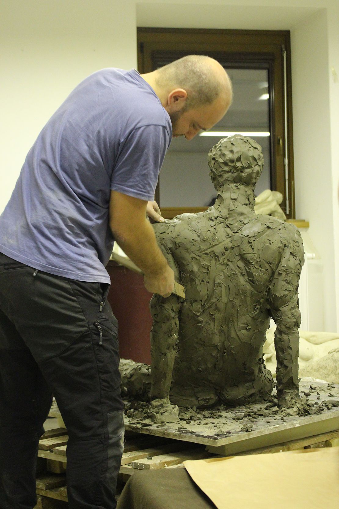 Modeling a real-size seated figure in clay.