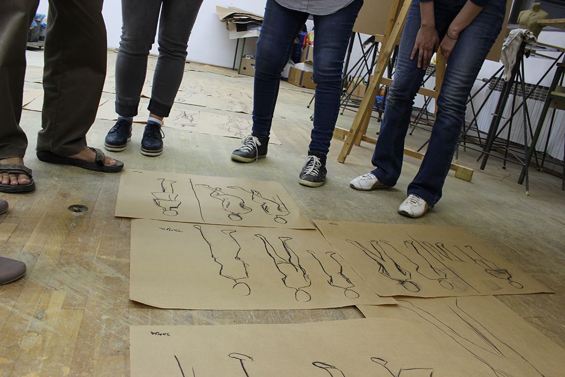 Tens of sketches spread on the studio floor, close up.