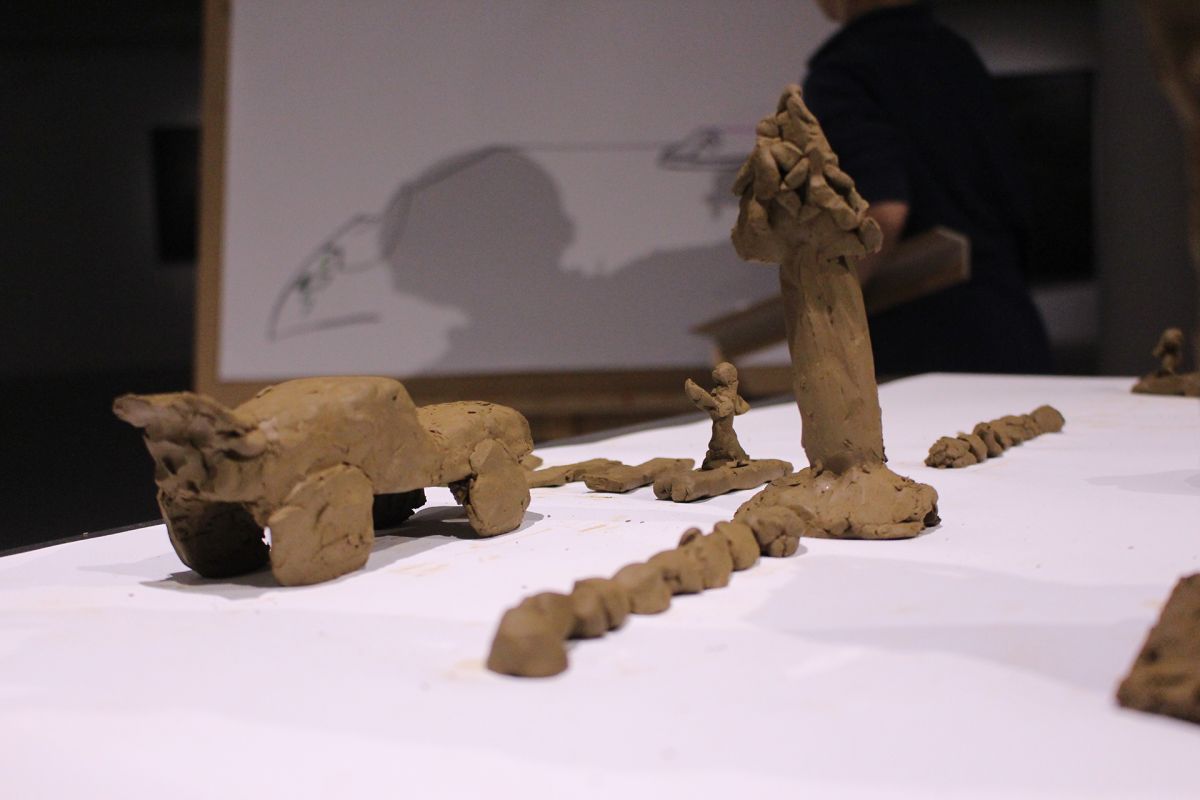 Children modeling playground in clay, from the side.